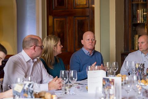 Photograph of roundtable attendees, focused on DWF partner Paul Holmes mid-conversation. He wears a blue chequered shirt with a blue jumper over the top.